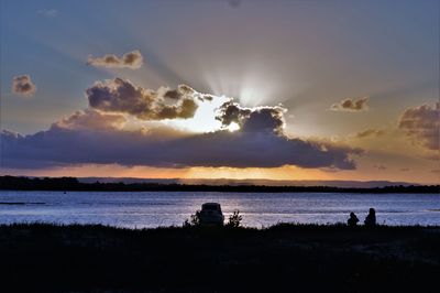 Silhouette people on beach against sky during sunset