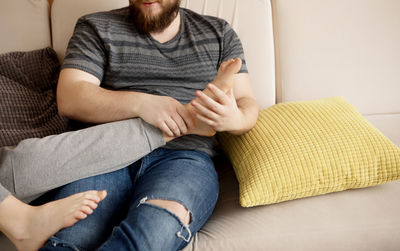 Midsection of couple sitting on sofa at home