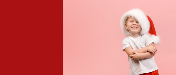 Portrait of a smiling girl standing against red background