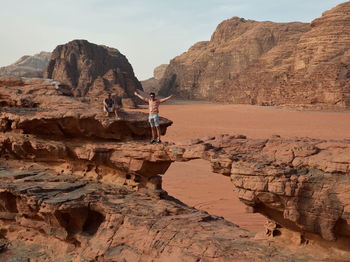Friends posing on rock formation in wadi rum desert in jordan