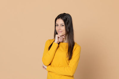 Portrait of smiling young woman against gray background