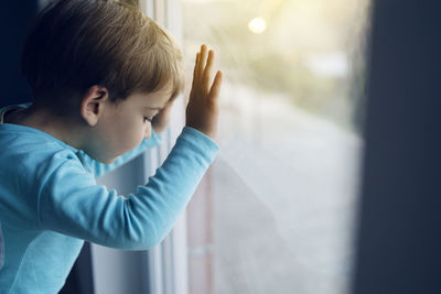 Close-up of boy looking through glass window