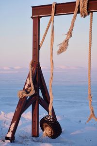 Low angle view of rope tied on wooden post against sky