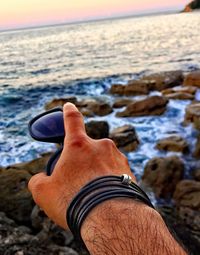 Close-up of hand against sea