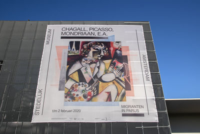 Low angle view of information sign against clear blue sky