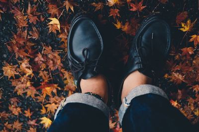 Low section of woman standing on autumn leaves