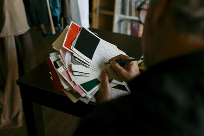 Male tailor writing on paper with pencil while working in studio