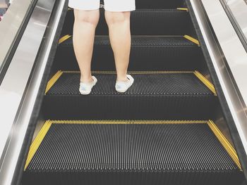 Low section of person standing on escalator at subway station