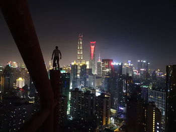 Illuminated modern buildings in city against sky at night