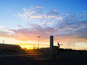 Road by city against sky during sunset