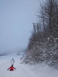 People on snow covered landscape against clear sky