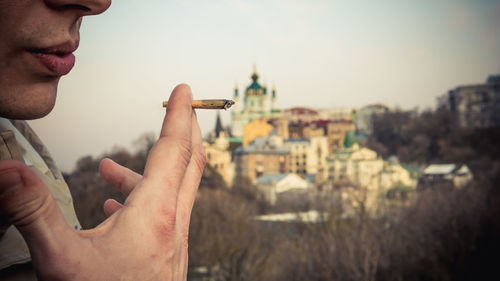 Midsection of man holding hands against buildings in city