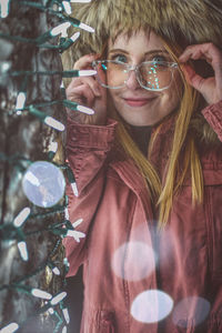 Portrait of smiling woman in fur coat by illuminated christmas decoration