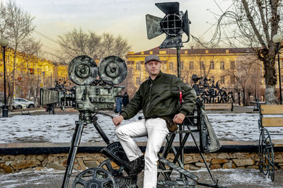 Portrait of man sitting on the monument of camera