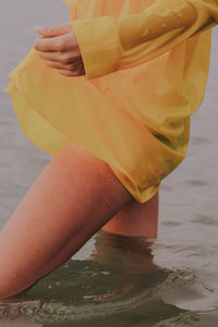 Low section of woman holding umbrella at beach