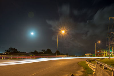 Light trails on road against sky at night