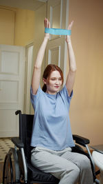 Young woman exercising while sitting on wheelchair