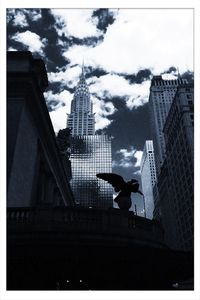 Low angle view of skyscrapers against cloudy sky