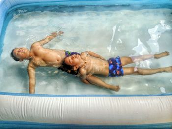 High angle view of brothers in inflatable swimming pool