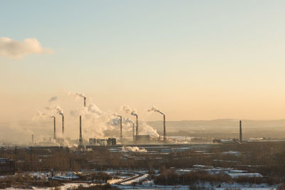 Smoke emitting from factory against sky