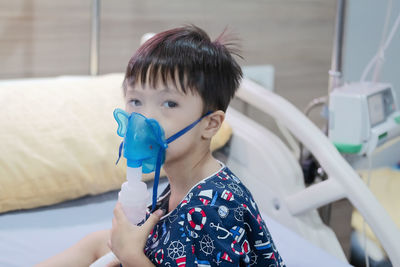 Portrait of cute boy wearing oxygen mask at hospital