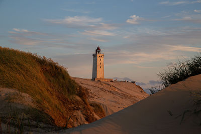 Lighthouse by sea against sky