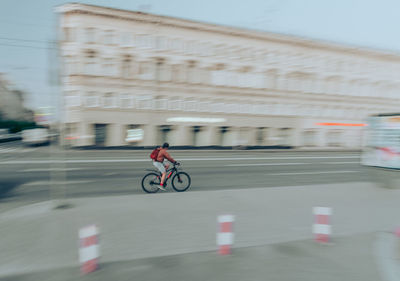 Blurred motion of man riding bicycle on road