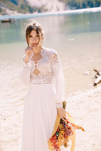 Portrait of bride holding bouquet standing at riverbank