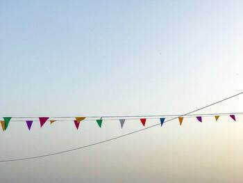 Low angle view of bunting flags against clear sky