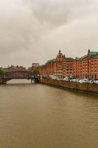 View of buildings at waterfront against cloudy sky