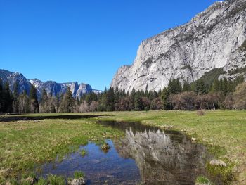 Scenic view of lake and mountains against clear blue sky