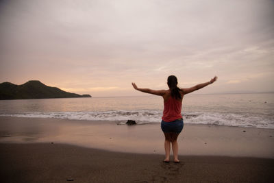 Full length rear view of woman standing on beach