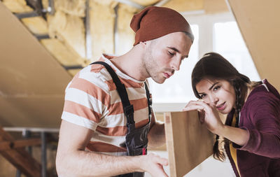 Couple measuring wooden plank at home