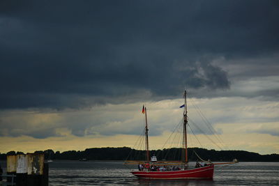 Sailboats in sea against storm clouds