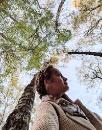 Low angle view of woman looking at tree trunk