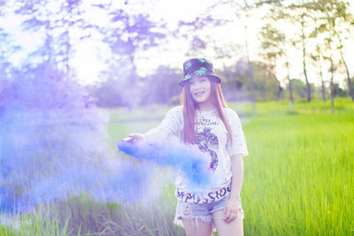 Portrait of woman holding distress flare while standing by plants