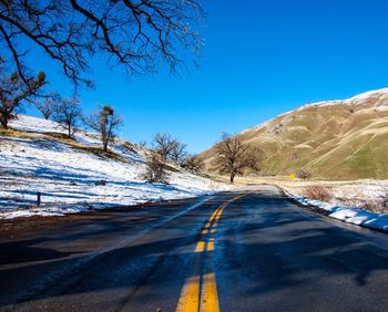 Road amidst trees against sky during winter