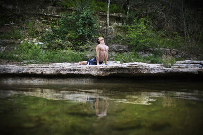 Man practicing yoga in upward facing dog pose by lake