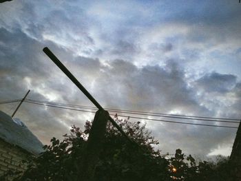 Low angle view of power lines against cloudy sky