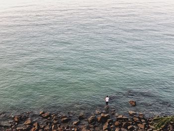 High angle view of people standing on rock in sea