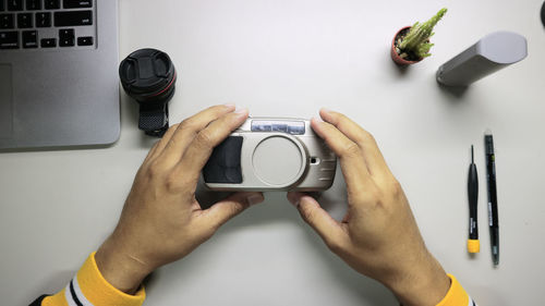 Cropped hands of man holding camera at table