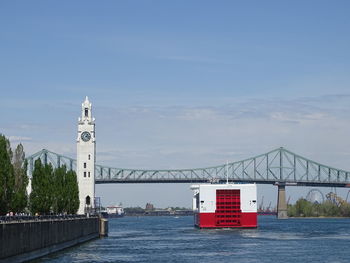 Bridge over river by building against sky
