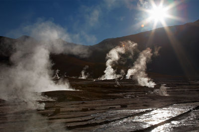 Smoke emitting from waterfall against sky