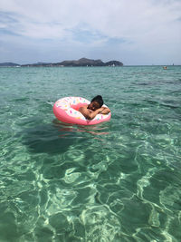 Woman floating in sea using inflatable ring