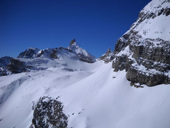 Scenic view of snow covered mountains against clear blue sky