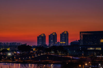 Illuminated buildings against sky at sunset