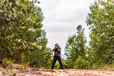 Full length of man standing by tree against sky