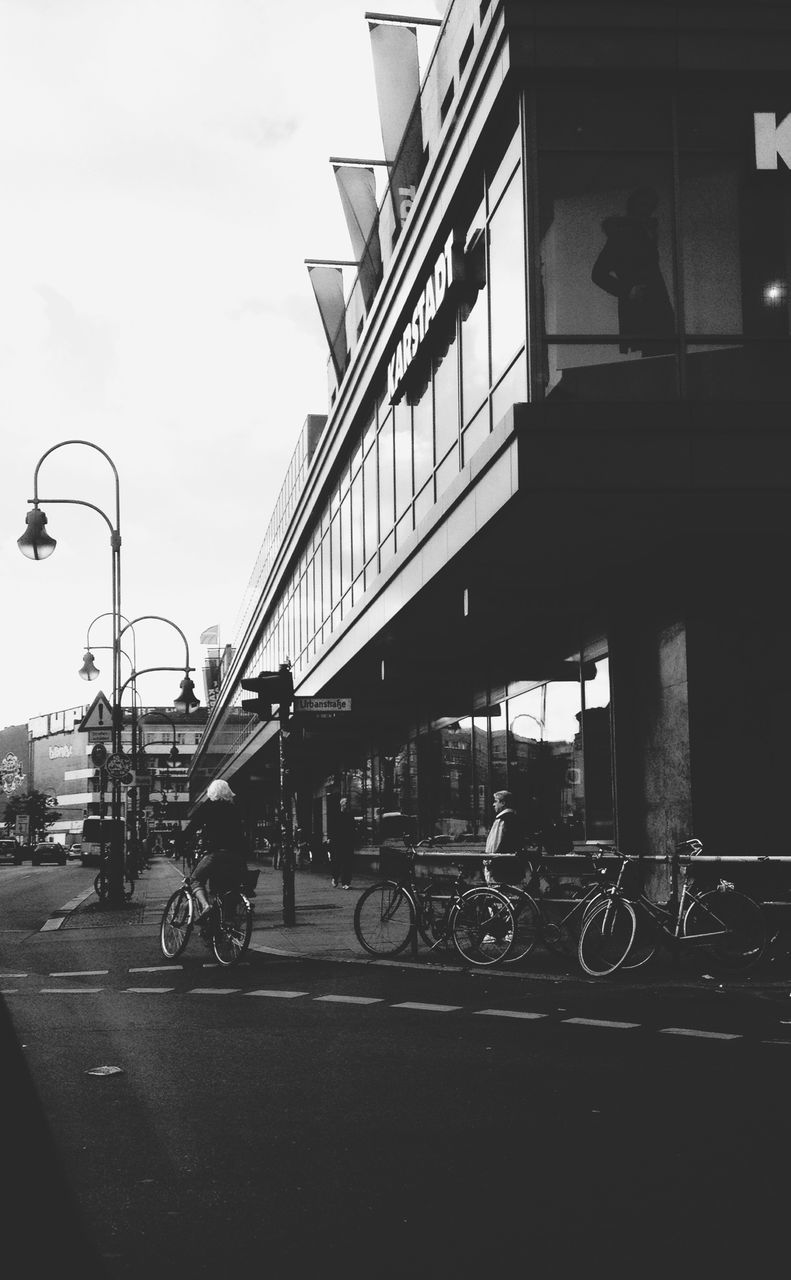 transportation, land vehicle, mode of transport, bicycle, architecture, built structure, building exterior, street, car, road, parked, city, stationary, parking, on the move, sky, travel, city life, men