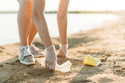 Low section of woman standing on sand at beach