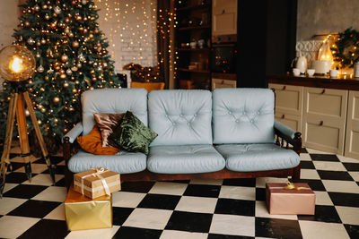 Christmas decorated interior of a loft style room in a cozy house, sofa and gift boxes  tree